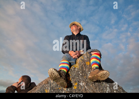 Uomo seduto su di una pietra in re prato, Glastonbury Festival 2011 Foto Stock