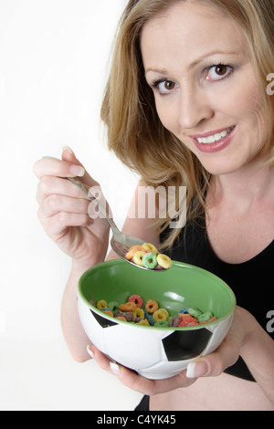 Donna mangiare una tazza di cereali colorati da una ciotola verde lifestyle shot Foto Stock