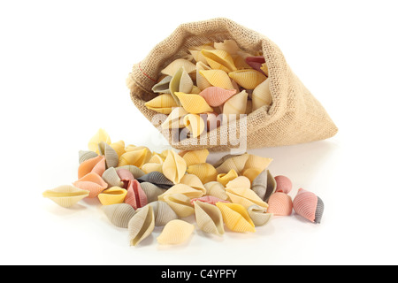 Una manciata di pasta colorata in un sacchetto su sfondo bianco Foto Stock