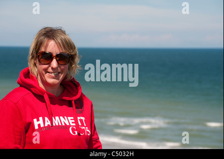 Donna che indossa gli occhiali da sole godendo una giornata di sole in spiaggia a Cromer, Norfolk, Inghilterra. Foto Stock