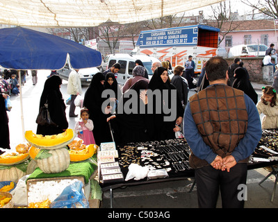 Turchia Istanbul distretto occidentale una più conservatore quartiere islamico. Le donne in nero Burka shopping al mercato aperto Foto Stock