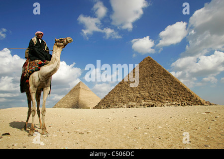 Un beduino tribesman e il suo cammello davanti alle piramidi di Giza, Cairo, Egitto. Foto Stock