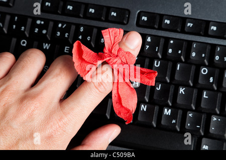 Arco rosso sul dito e della tastiera del computer Foto Stock