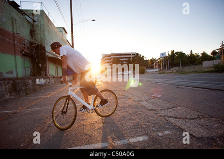 L'uomo fare acrobazie in bicicletta sulla strada di città Foto Stock