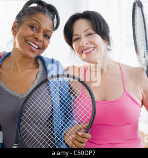 Amici in piedi insieme con racchette da tennis Foto Stock