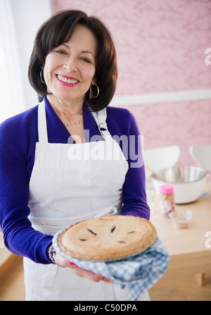 Razza mista donna che mantiene fresca torta al forno Foto Stock