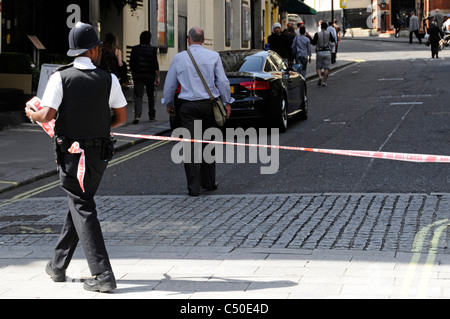 Funzionario di polizia di stendere il nastro per delimitare l accesso a "Strand' a Londra a causa di grave incidente Foto Stock