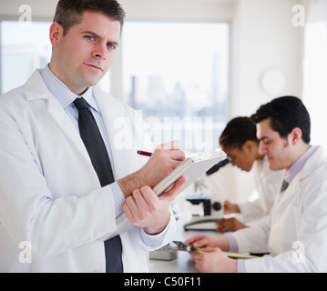 Scienziato iscritto negli appunti in laboratorio Foto Stock