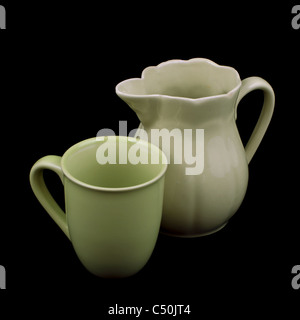 Vecchia ceramica verde brocca e tazza isolata su sfondo nero Foto Stock