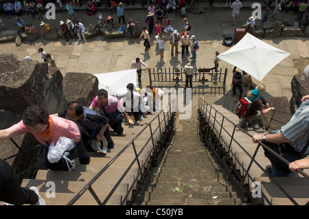 I turisti a salire la ripida scalinata che conduce al terzo livello di Angkor Wat, Angkor, Siem Reap, Cambogia Foto Stock