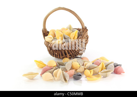 Una manciata di pasta colorata in un cesto su sfondo bianco Foto Stock