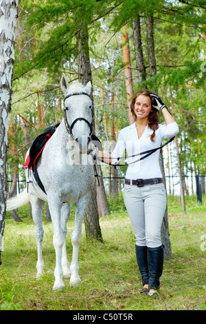 Immagine della femmina felice guardando la fotocamera a cavallo nelle vicinanze Foto Stock