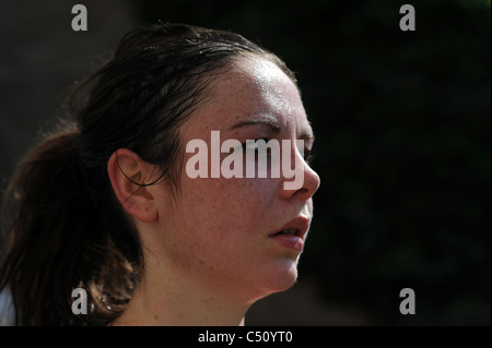 Giovane donna cercando accaldato con il sudore sulla fronte dopo corsa mattutina in temperatura calda Foto Stock