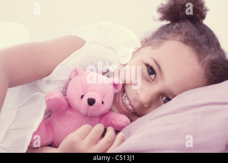 Bambina giacente sul letto con Teddy bear Foto Stock