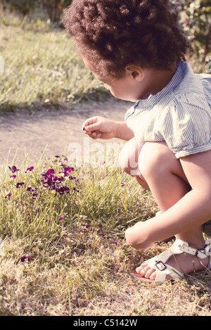 Bambina guardando un petalo nella sua mano Foto Stock