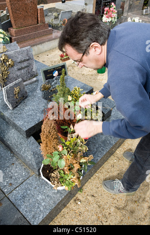 L'uomo tende a piante in vaso a recinto nel cimitero Foto Stock