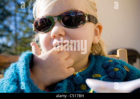 Baby girl mettendo il cibo in bocca, ritratto Foto Stock