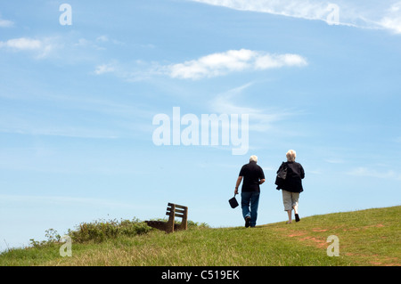 Coppia di mezza età passeggiata banco passato verso il cielo blu,saga,il pensionamento,più tempo,famiglia,futuro luminoso,bianco etnicità| vicino, Foto Stock