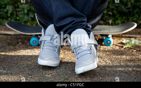 Uomo seduto sul suo skateboard Foto Stock