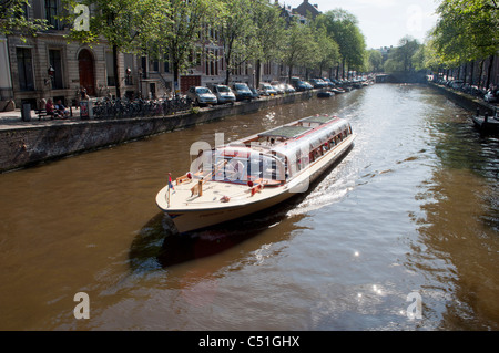 Una chiatta vele verso il basso di un canale pittoresco della città olandese di Amsterdam. Foto Stock