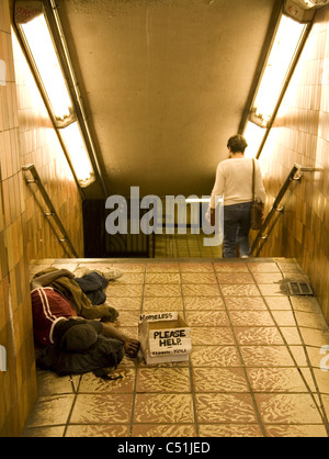 Senzatetto uomo dorme in metropolitana e ingresso/uscita, Rockefeller Center di New York City. Foto Stock