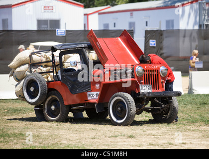 Un uomo sotto il cofano di un sovraccarico Jeep Willys Foto Stock