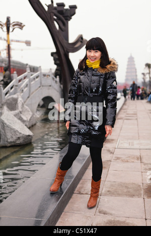 Giovane donna cinese in piedi su una strada in Xian e sorridente, Cina Foto Stock
