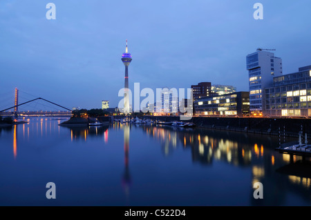 Scena notturna di media Harbour (Medienhafen) con torre Rheinturm e Neuer Zollhof edificio di Frank Gehry, Duesseldorf Foto Stock