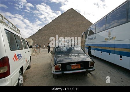 Autobus e auto parcheggiate accanto alla grande Piramide di Khufu sull'altopiano di Giza in Egitto Foto Stock