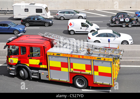 Vista da sopra guardando in giù a Essex Fire & Rescue vigili del fuoco motore M25 Autostrada equipaggio frequentare car crash incidente inferiore adiacente ponticello England Regno Unito Foto Stock