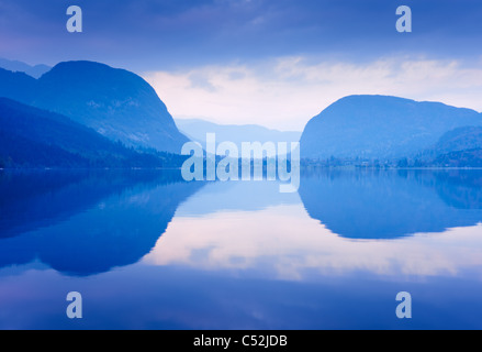 Montagne blu riflessa in acqua di lago. Il lago di Bohinj, Slovenia. Foto Stock