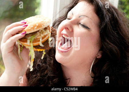 Donna di mangiare cibo grasso Foto Stock