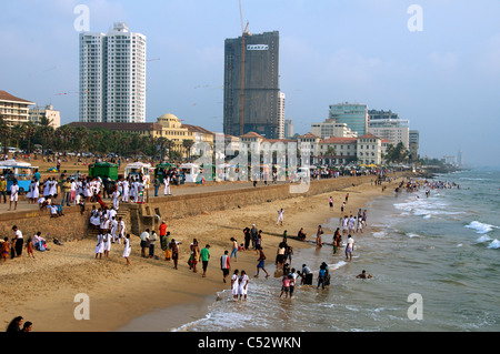Persone sguazzare a waters edge Galle Face Green Beach nel tardo pomeriggio Colombo Sri Lanka Foto Stock