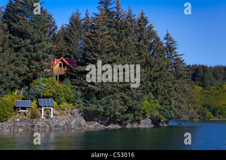 Vista panoramica di un log home alimentato da pannelli solari in Anton Larsen Bay, isola di Kodiak, Southwest Alaska, estate Foto Stock