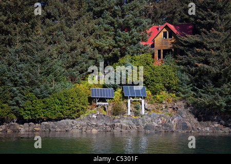 Vista panoramica di un log home alimentato da pannelli solari in Anton Larsen Bay, isola di Kodiak, Southwest Alaska, estate Foto Stock