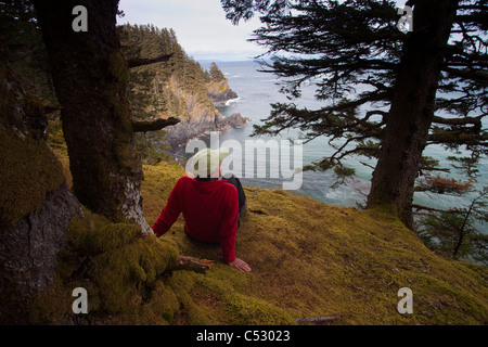 Escursionista femmina in appoggio, Chiniak Bay a Fort Abercrombie stato storico parco sulla isola di Kodiak, Alaska Foto Stock