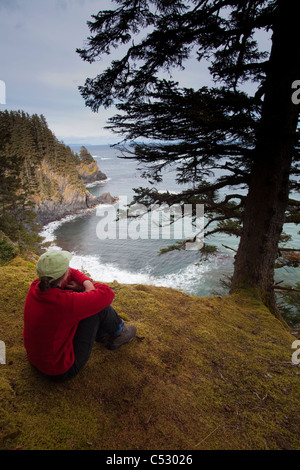 Escursionista femmina in appoggio, Chiniak Bay a Fort Abercrombie stato storico parco sulla isola di Kodiak, Alaska Foto Stock