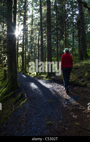 Donna escursioni attraverso Sitka Spruce alberi intorno al lago di Gertrude in Fort Abercrombie stato storico Park, isola di Kodiak, Alaska Foto Stock