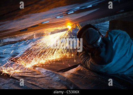 Operatore taglia raccordi di metallo fuori dello scafo di una barca, Kodiak cantiere, Saint Herman Harbour, Kodiak, vicino Isola, Alaska Foto Stock