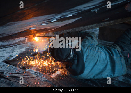 Operatore taglia raccordi di metallo fuori dello scafo di una barca, Kodiak cantiere, Saint Herman Harbour, Kodiak, vicino Isola, Alaska Foto Stock