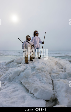 Inupiaq eschimese cacciatori in eskimo trasportare un fucile e bastone mentre guardano il mare Chukchi, Barrow, Alaska Foto Stock