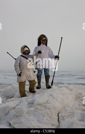 Inupiaq eschimese cacciatori in eskimo trasportare un fucile e bastone mentre guardano il mare Chukchi, Barrow, Alaska Foto Stock