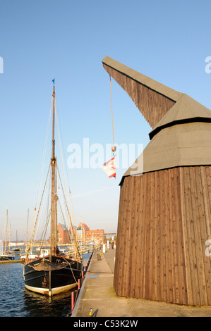 L uomo medievale-powered gru di carico e la barca a vela nel porto storico, città anseatica di Rostock, Meclemburgo-Pomerania Occidentale Foto Stock