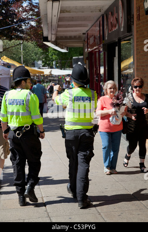 Due poliziotti in alta visability giacche su city shopping street Foto Stock