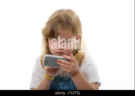 Ragazza di età primaria giocando con un iphone/ipod touch contro un bianco semplice sfondo per studio. Foto Stock