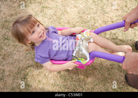 Femmina posa toddler ruota in Barrow Foto Stock