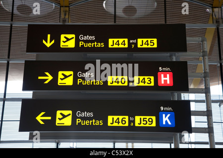 Aeroporto lotta gate di partenza segno scritto in inglese e spagnolo contro la finestra nel moderno aeroporto Foto Stock