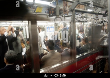 I passeggeri che viaggiano in un treno della metropolitana di Tokyo, Giappone Foto Stock