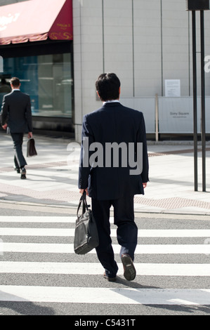 Due imprenditori camminando sulla strada, Ginza Chuo Ward, Tokyo, Giappone Foto Stock