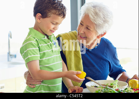Donna senior di preparare il cibo in una cucina con suo nipote Foto Stock